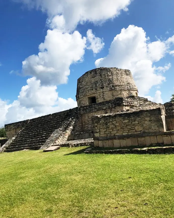 En la imagen se observa una antigua estructura maya de piedra, con una construcción circular en la parte superior y una escalinata a un lado.