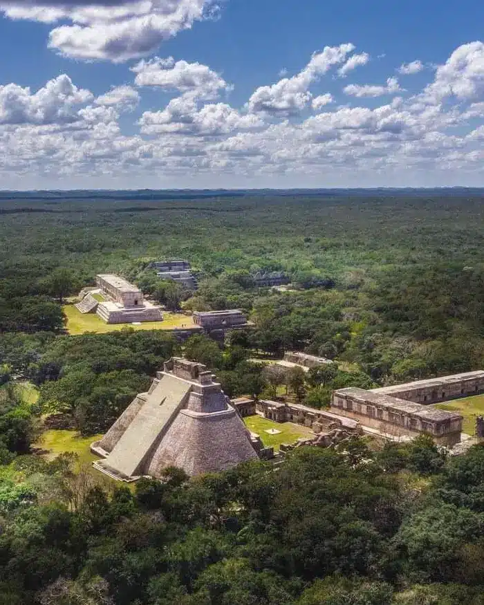 La pirámide principal destaca por su forma elevada y sus muros de piedra, mientras alrededor se observan otros edificios arqueológicos más pequeños.