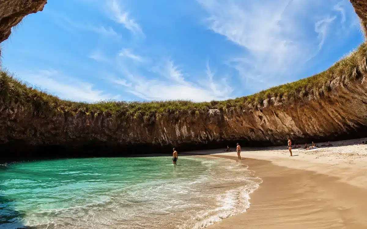 El agua cristalina contrasta con el tono cálido de la arena y las paredes rocosas que rodean el lugar.