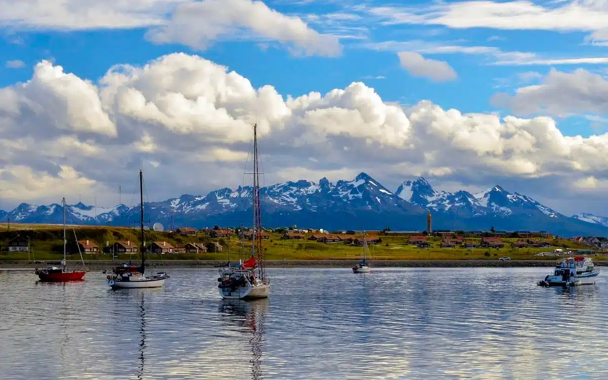 La imagen muestra la bahía de Ushuaia en calma, con veleros anclados frente a la ciudad.