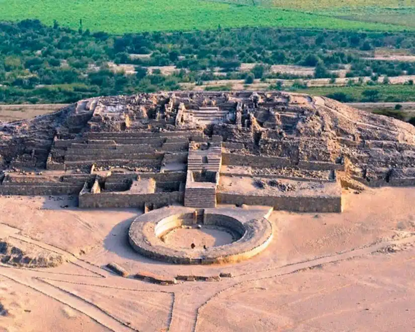 Aerial view of Caral showing ancient pyramidal structures and a circular sunken plaza in the desert valley
