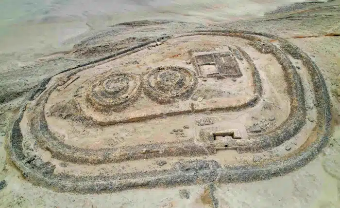 Aerial view of Chankillo archaeological complex with circular stone structures and defensive walls in a desert landscape