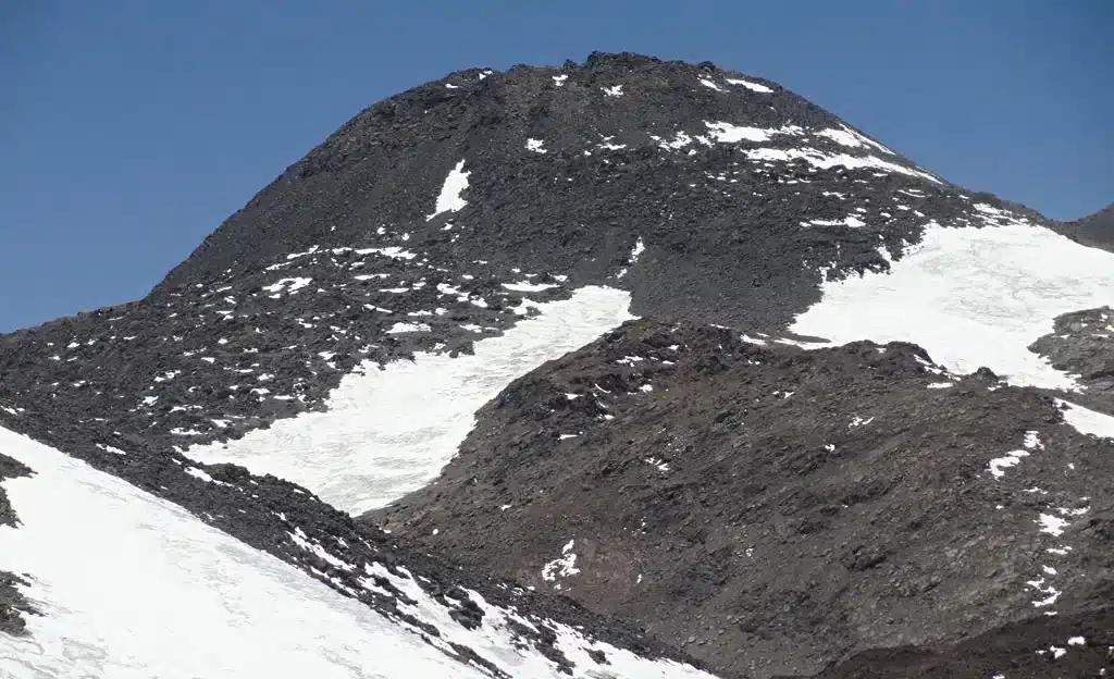Rocky Cazadero or Walther Penck summit with patchy snow beneath a clear Andean sky