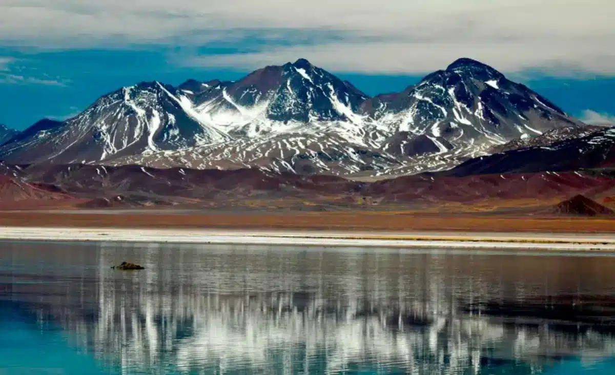 Snow-capped mountains reflected in a high-altitude lagoon at Nevado Tres Cruces National Park in the Chilean Andes