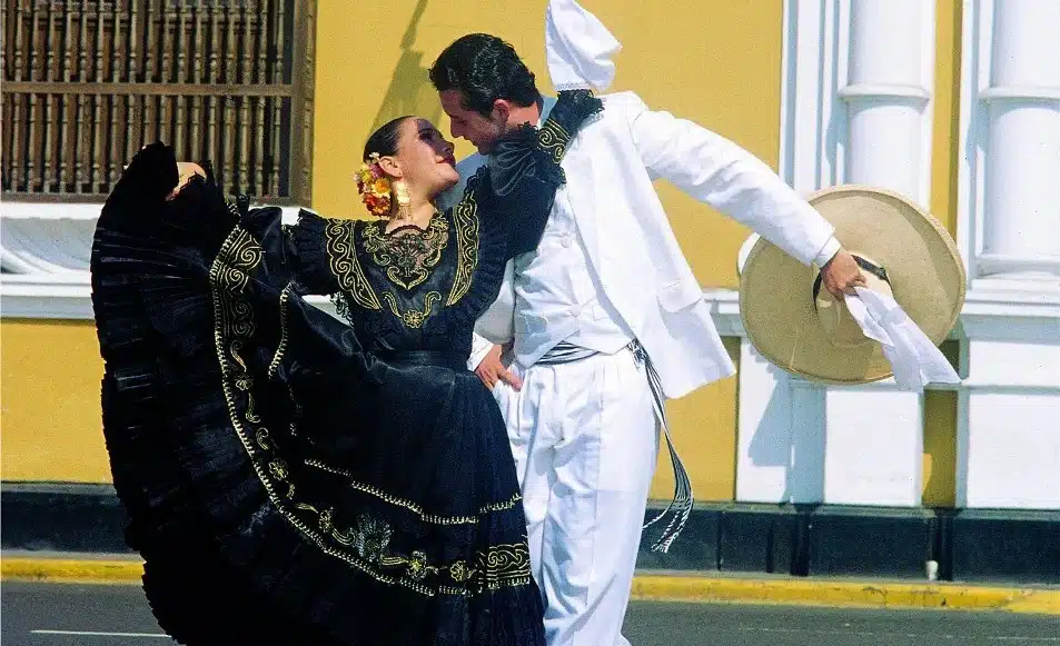 Pareja bailando marinera norteña con vestuario tradicional, pañuelo blanco y traje típico peruano