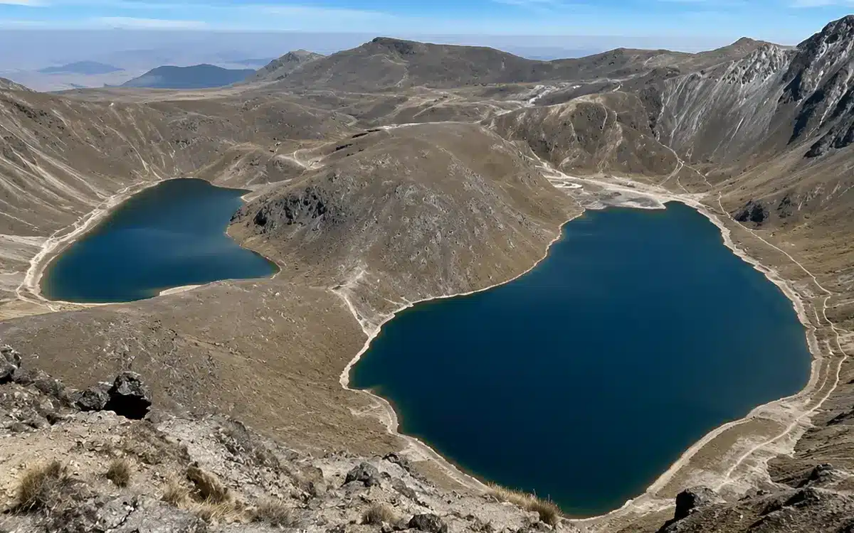 En la imagen se observan dos lagunas de color azul intenso ubicadas dentro de un paisaje volcánico de alta montaña.