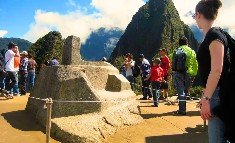Una turista observa el Intihuatana, maravillada por la precisión y el conocimiento ancestral de los incas.