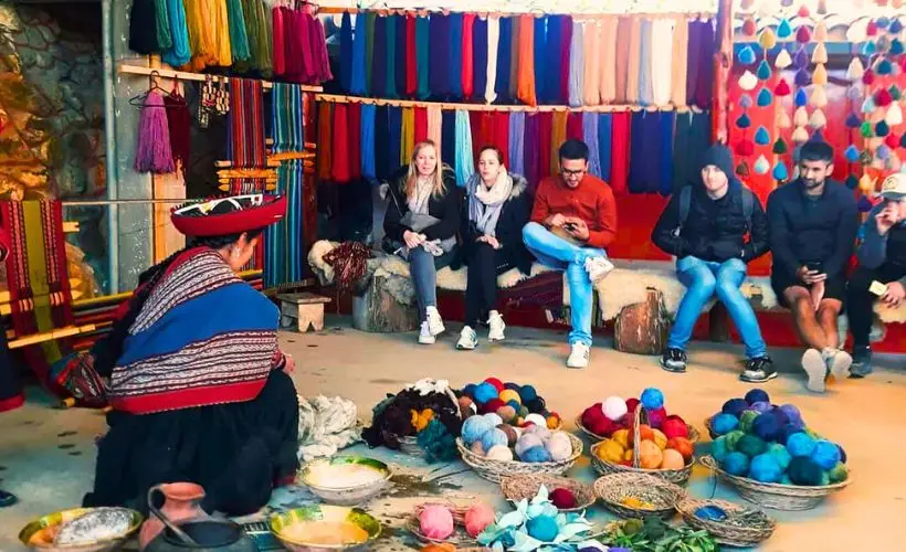 Turistas observan el proceso tradicional de teñido de la lana en el distrito de Chinchero.