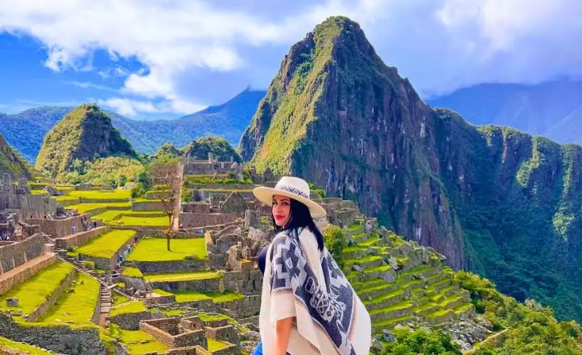 A traveler enjoys a bright and sunny day visiting the majestic Machu Picchu ruins.
