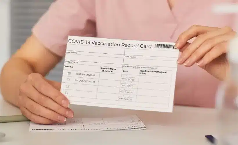Traveler holding international vaccination card at airport check-in counter, showing that vaccines for Peru are recommended but not mandatory for entry in 2025.