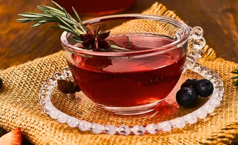 Steaming cup of anise tea served with herbs on a wooden table