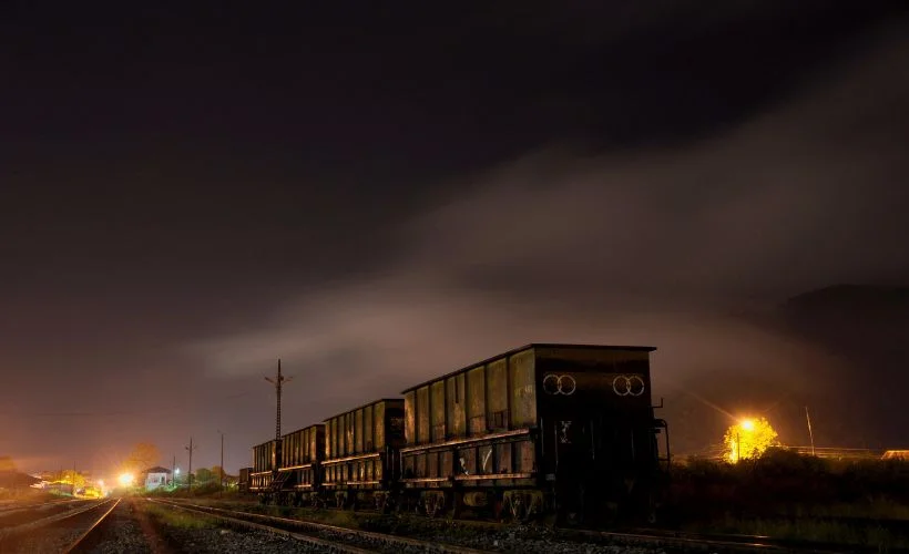 A train crossing the high Andean plains at sunset on the route to Uyuni, Bolivia, surrounded by mountains and open landscapes under a golden sky.