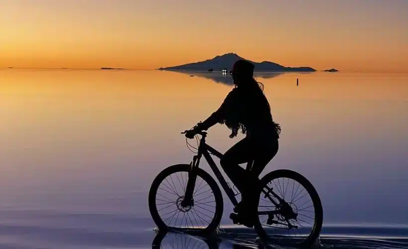 Viajera contempla el atardecer en el Salar de Uyuni mientras el cielo cambia de color sobre la superficie de sal