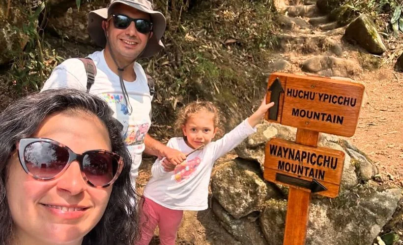 Family with daypacks follows stone steps on Huchuy Picchu in Machu Picchu, Cusco. Stable handrails, sunny weather, and nearby terraces make this short hike accessible for most visitors.