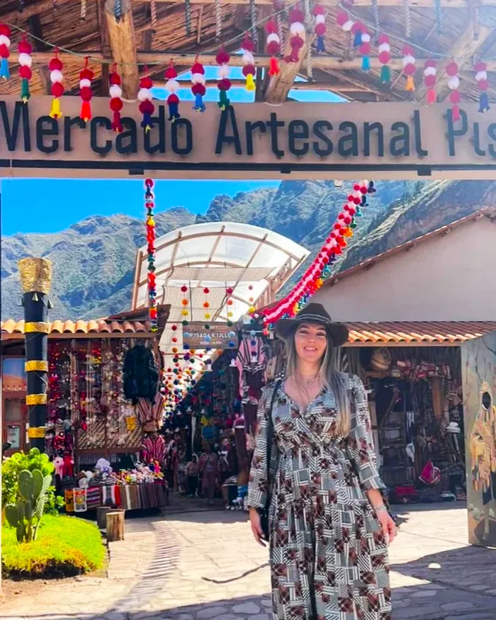 Una mujer posa sonriente en la entrada del Mercado Artesanal de Pisac, en el Valle Sagrado de los Incas.