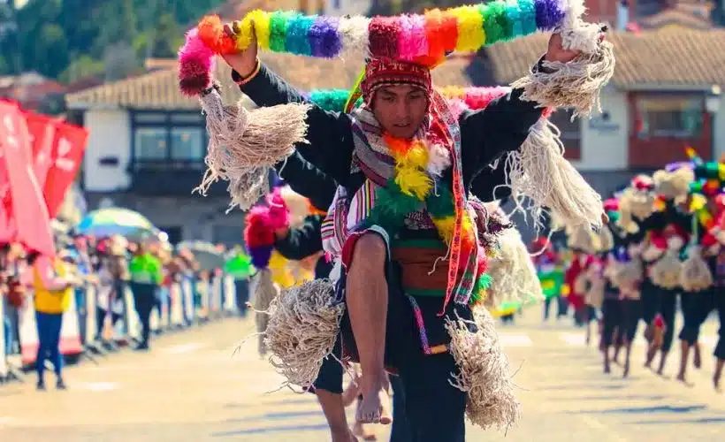 Men and women in colorful Quechua clothing perform a ceremonial dance in fields near Cusco, offering corn and flowers to Pachamama during an ancestral harvest ritual.