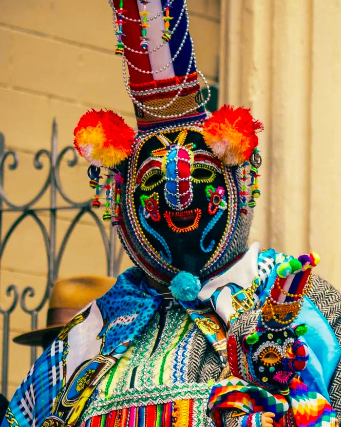 A Kusillo dancer wearing a colorful mask and traditional costume performs during the Virgin of Candelaria festival, entertaining visitors with energetic movements and Andean cultural symbolism.