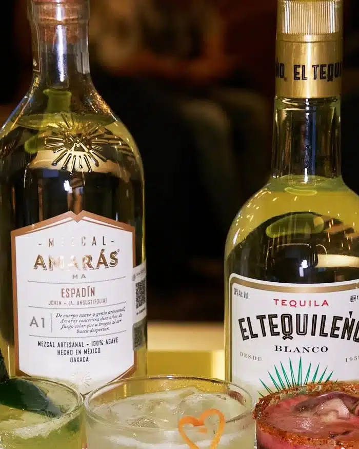 Una botella de mezcal y otra de tequila acompañan bebidas refrescantes con presentaciones únicas.