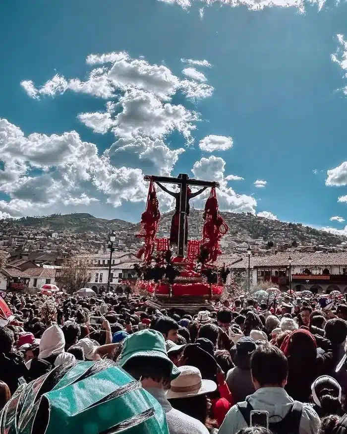 A large crowd fills Cusco’s Plaza de Armas as people follow the Lord of the Earthquakes procession, surrounded by colonial buildings under clear daylight.