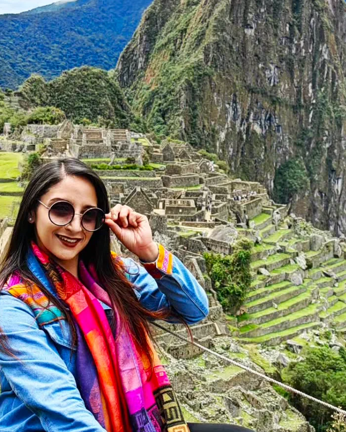 Una viajera sonriente posa frente al imponente santuario histórico de Machu Picchu.