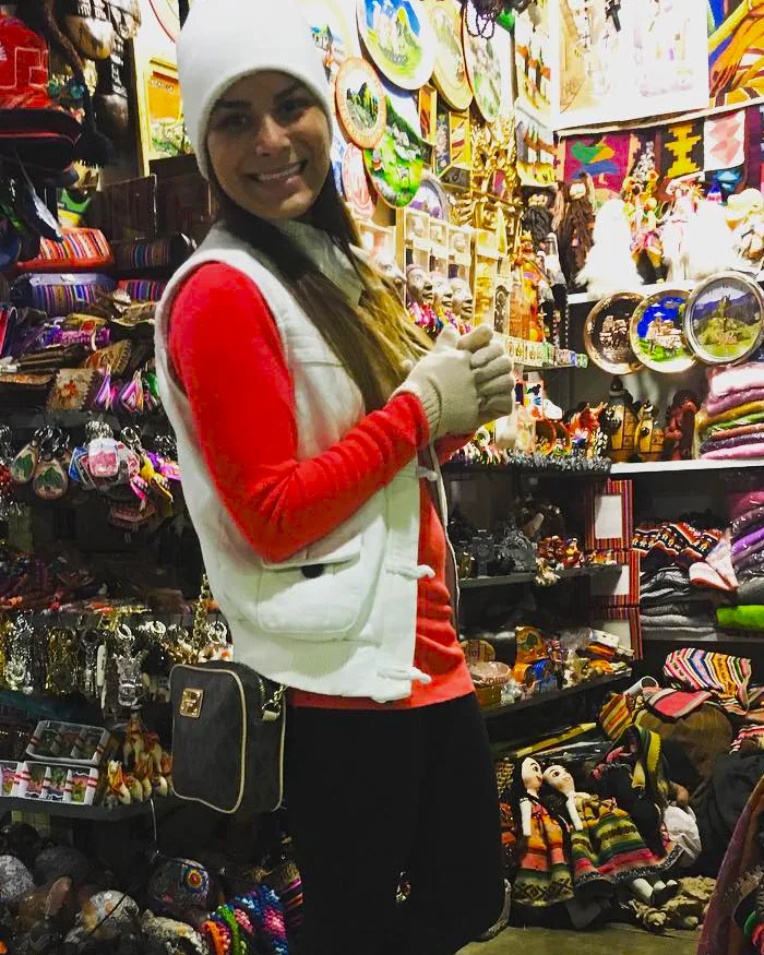 A su alrededor se observan coloridos tejidos, mantas, bufandas y bolsos elaborados con motivos tradicionales.