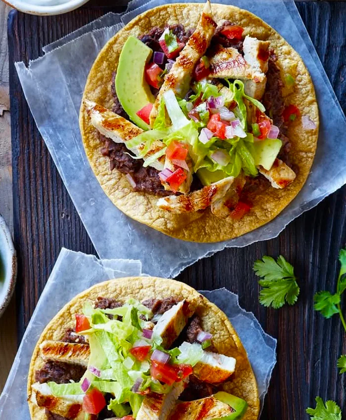Cada tostada tiene una base de tortilla crujiente cubierta con frijoles refritos.