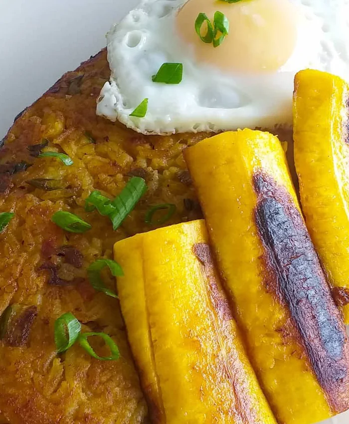 Encima del tacu tacu descansa un huevo frito con la yema brillante y ligeramente cremosa.