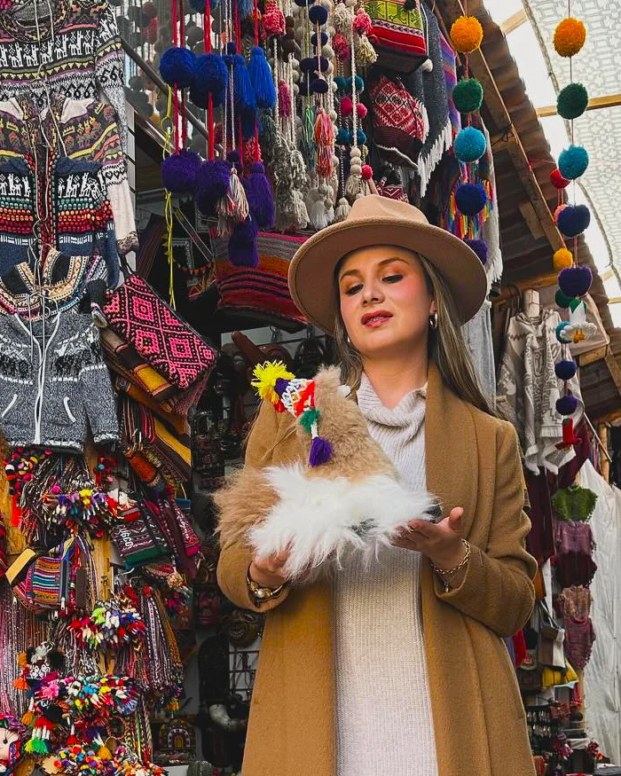 Ella sostiene en sus manos una pequeña figura decorativa de alpaca con detalles festivos.