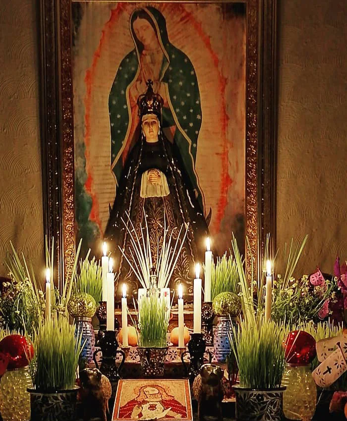 Se aprecian pequeños banderines de papel picado en tonos rosados y morados, símbolos tradicionales de fe y devoción.