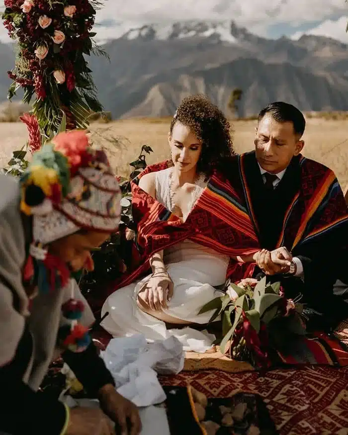 Pareja durante una ceremonia andina rodeada de montañas en Perú