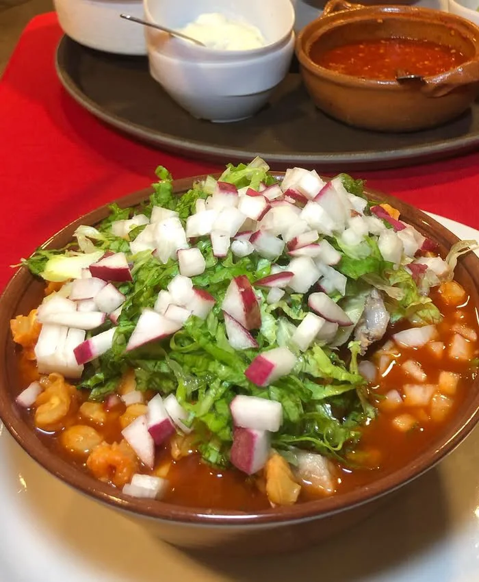 El caldo tiene un color rojizo intenso, resultado del chile guajillo usado en su preparación.