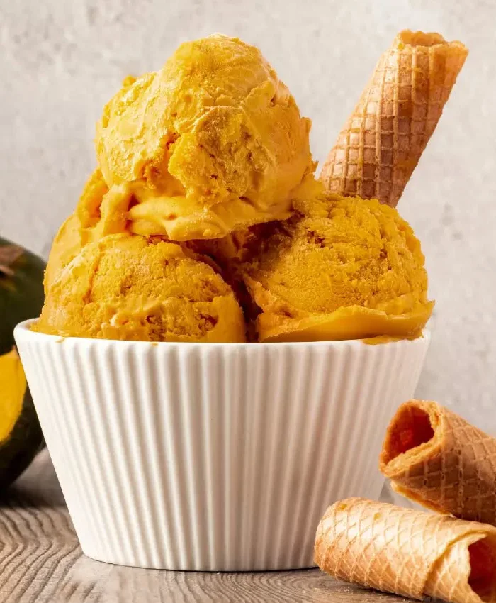 El postre muestra varias bolas de helado de color amarillo intenso, característico de la lúcuma peruana.