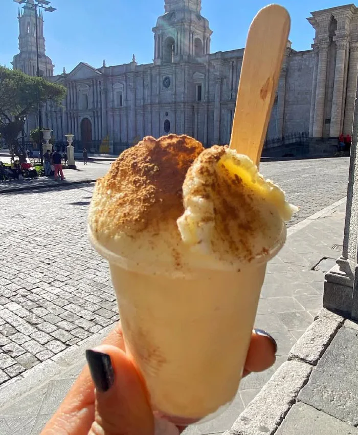 El postre está servido en un pequeño vaso de plástico, con una textura cremosa y un color marfil característico.