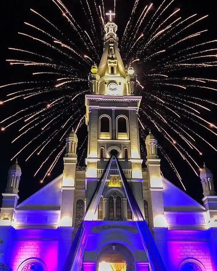 A neoclassical church facade rises under clear skies, showcasing tall columns and arches in the historic center of Peru during a religious celebration.