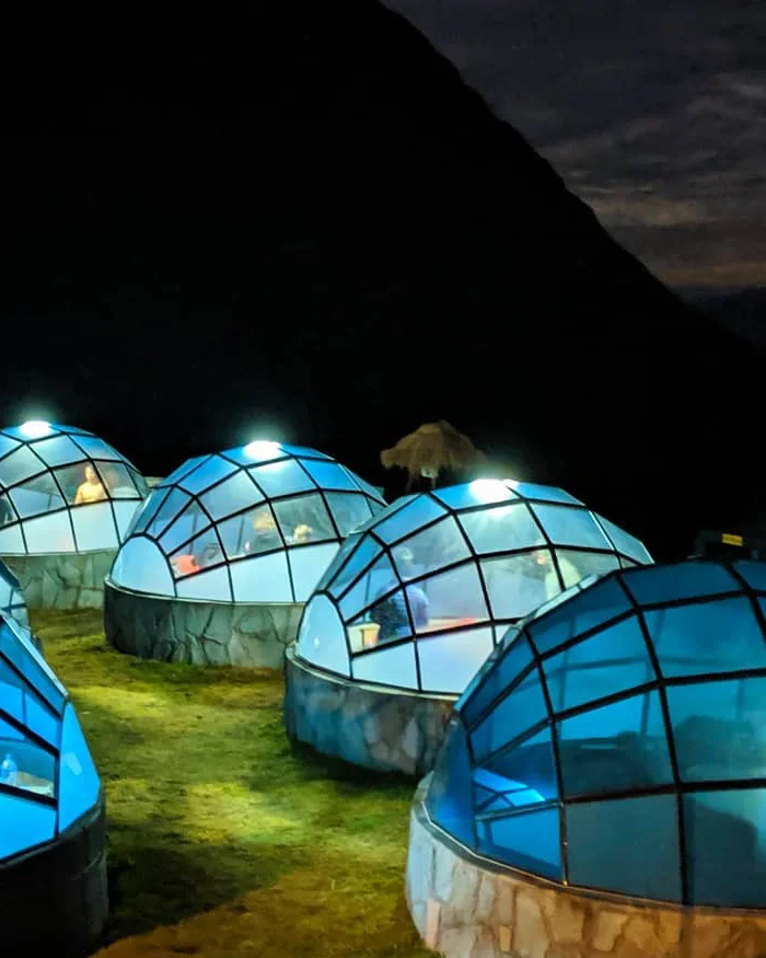 Las luces internas proyectan un brillo suave que se refleja en las paredes de vidrio, generando un efecto futurista y acogedor.