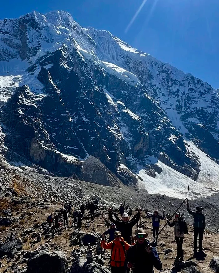 The snow-covered Salkantay Mountain rises sharply above rocky walls and scattered clouds, dominating the Andean landscape along the famous Cusco trekking route.