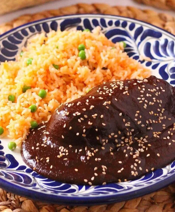 El mole cubre una pieza de pollo con una salsa espesa y oscura, característica por su mezcla de chiles y chocolate.