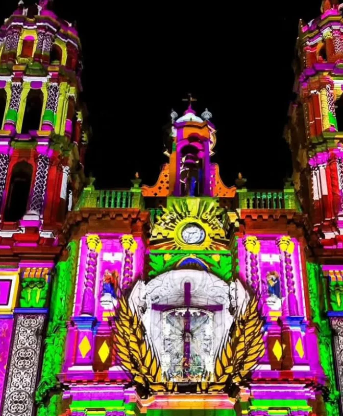 La proyección combina elementos religiosos con patrones decorativos modernos que cubren toda la fachada.