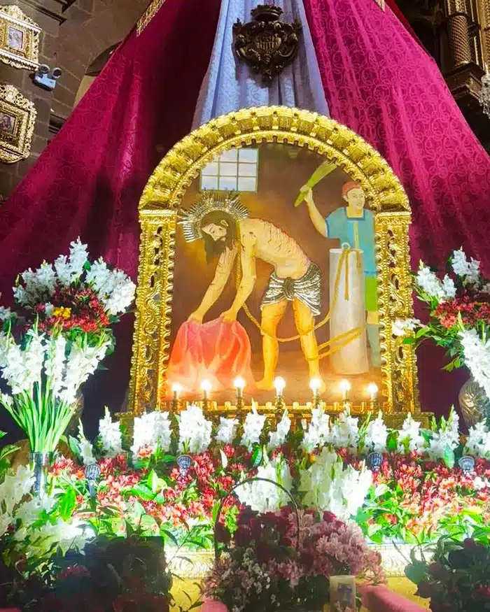 La pintura sagrada del Señor de Huanca se enmarca en un altar dorado rodeado de velas encendidas.