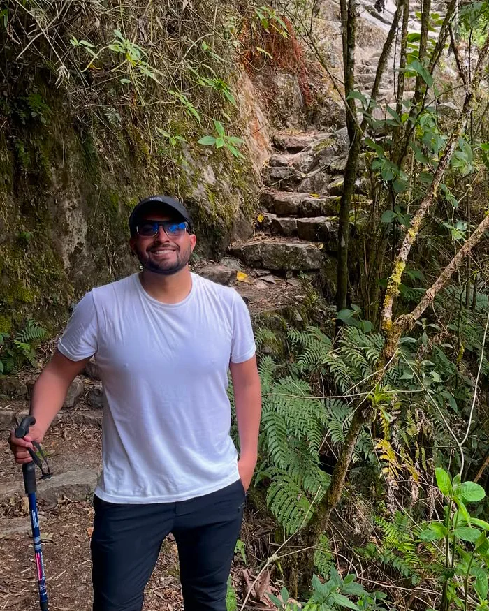 El viajero sonriente posa en medio de un sendero rodeado de vegetación frondosa.
