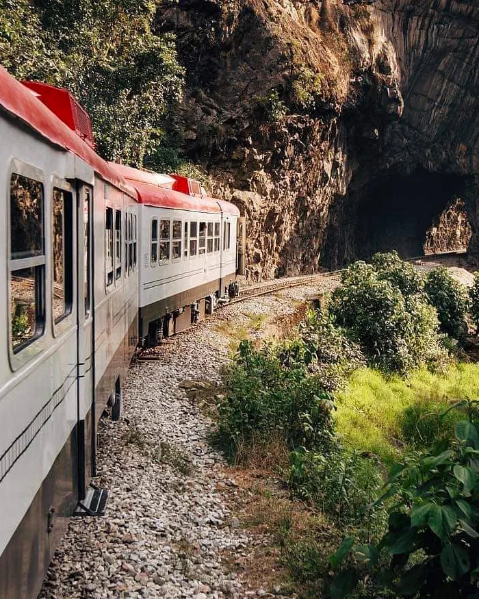 El tren avanza por una vía estrecha mientras se acerca a un túnel, rumbo a Machu Picchu