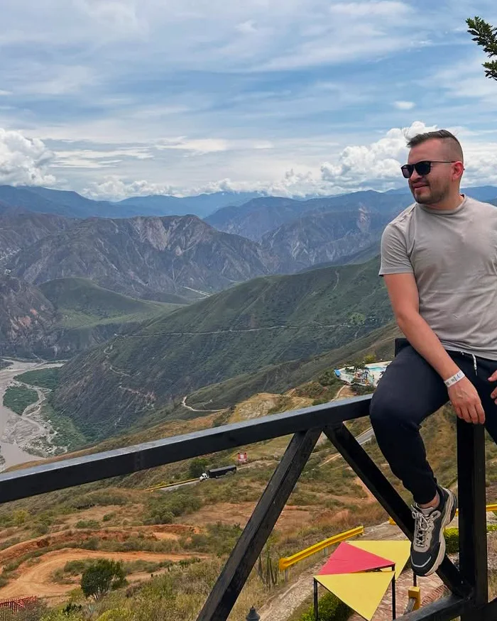 El viajero se sienta relajado frente al imponente Cañón del Chicamocha, disfrutando de una vista que corta la respiración.