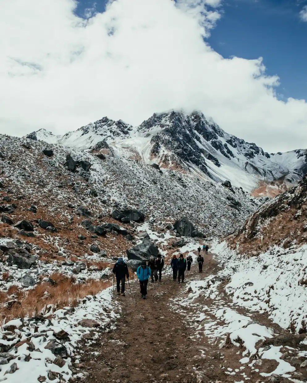 Grupo de excursionistas en la ruta del Salkantay en Perú, con laderas nevadas y picos escarpados al frente.