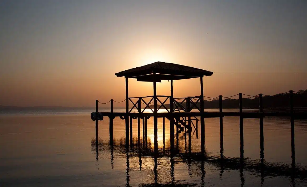 Atardecer en la costanera de San Bernardino con muelle, lago Ypacaraí y reflejo en el agua