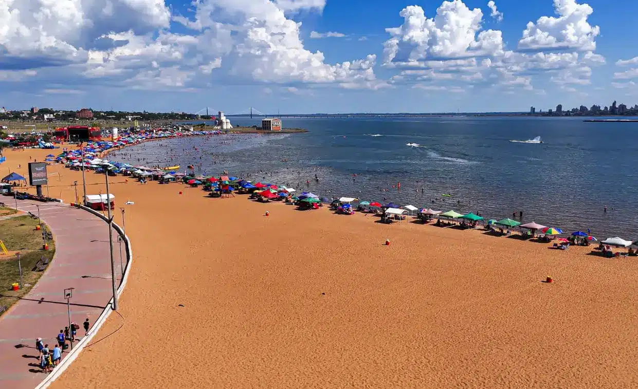 Playa San José en Encarnación con arena dorada, sombrillas y vista al río Paraná