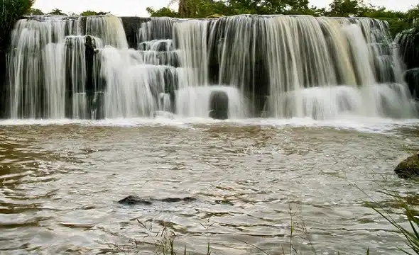 Cascada en el Parque Nacional Ybycuí con poza natural, rocas oscuras y vegetación verde
