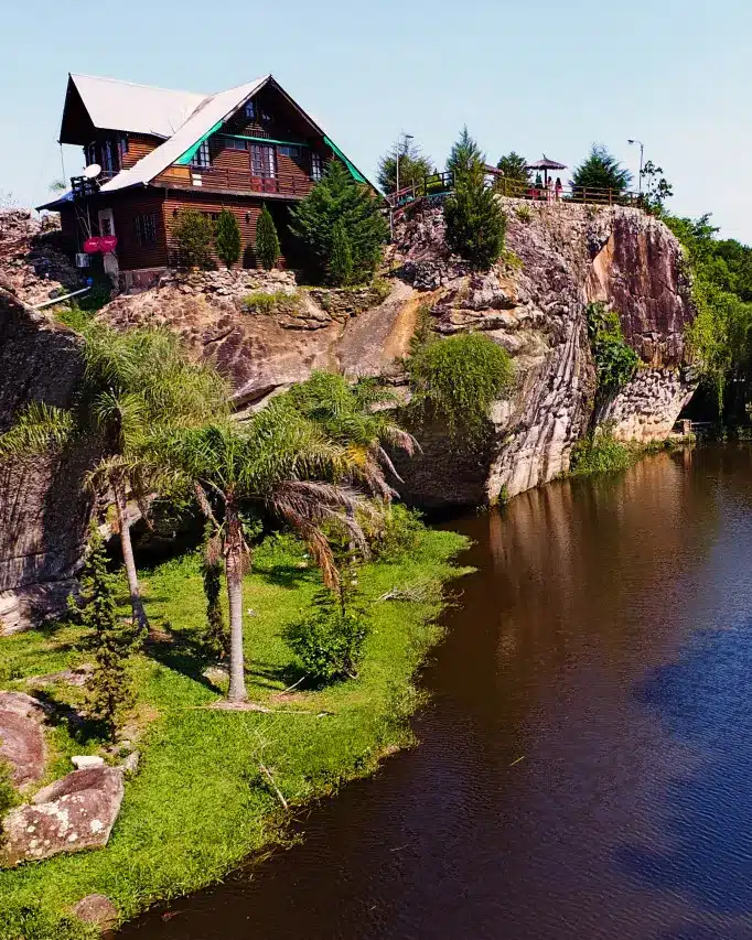Cabañas Ita Kua de madera sobre formaciones rocosas con laguna y vegetación en Paraguay