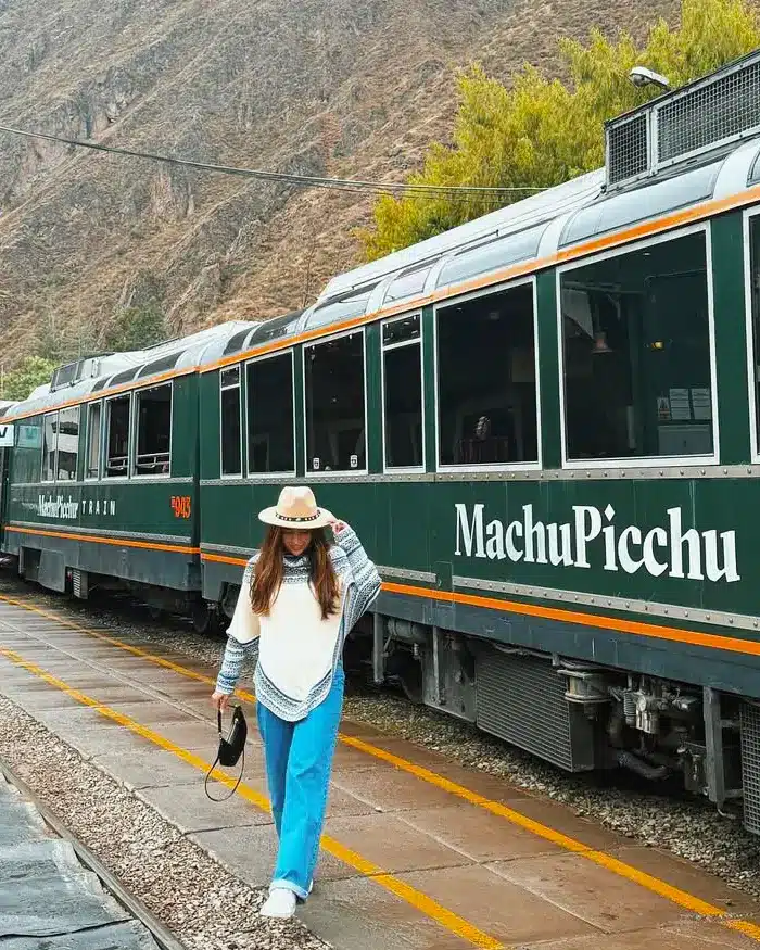 Viajera junto al tren a Machu Picchu en un paisaje del Valle Sagrado
