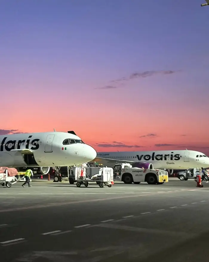 La imagen muestra dos aviones de Volaris en plataforma durante el atardecer, un escenario típico previo a vuelos de México a Perú.