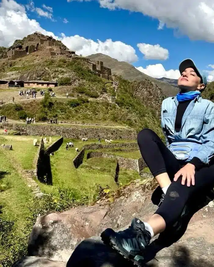 Viajera observando un sitio arqueológico entre montañas durante una ruta por Cusco